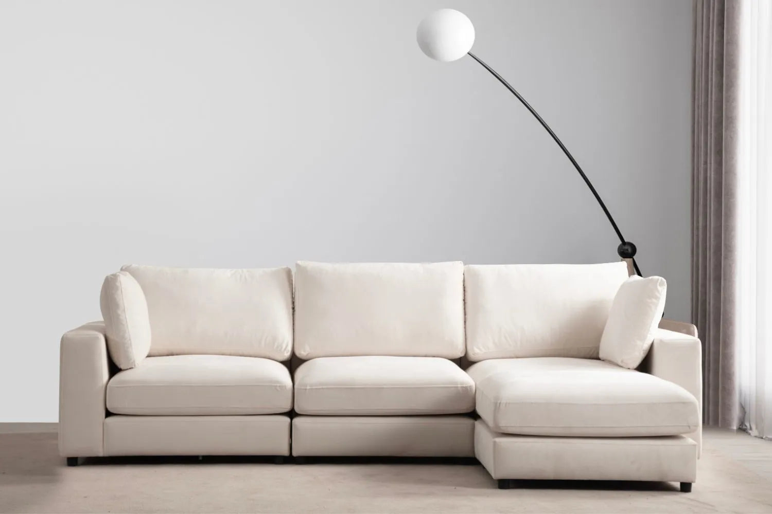Canapé JULIA modulable en velours blanc cassé 3 places avec pouf, mis en scène dans un salon moderne avec lampe design.