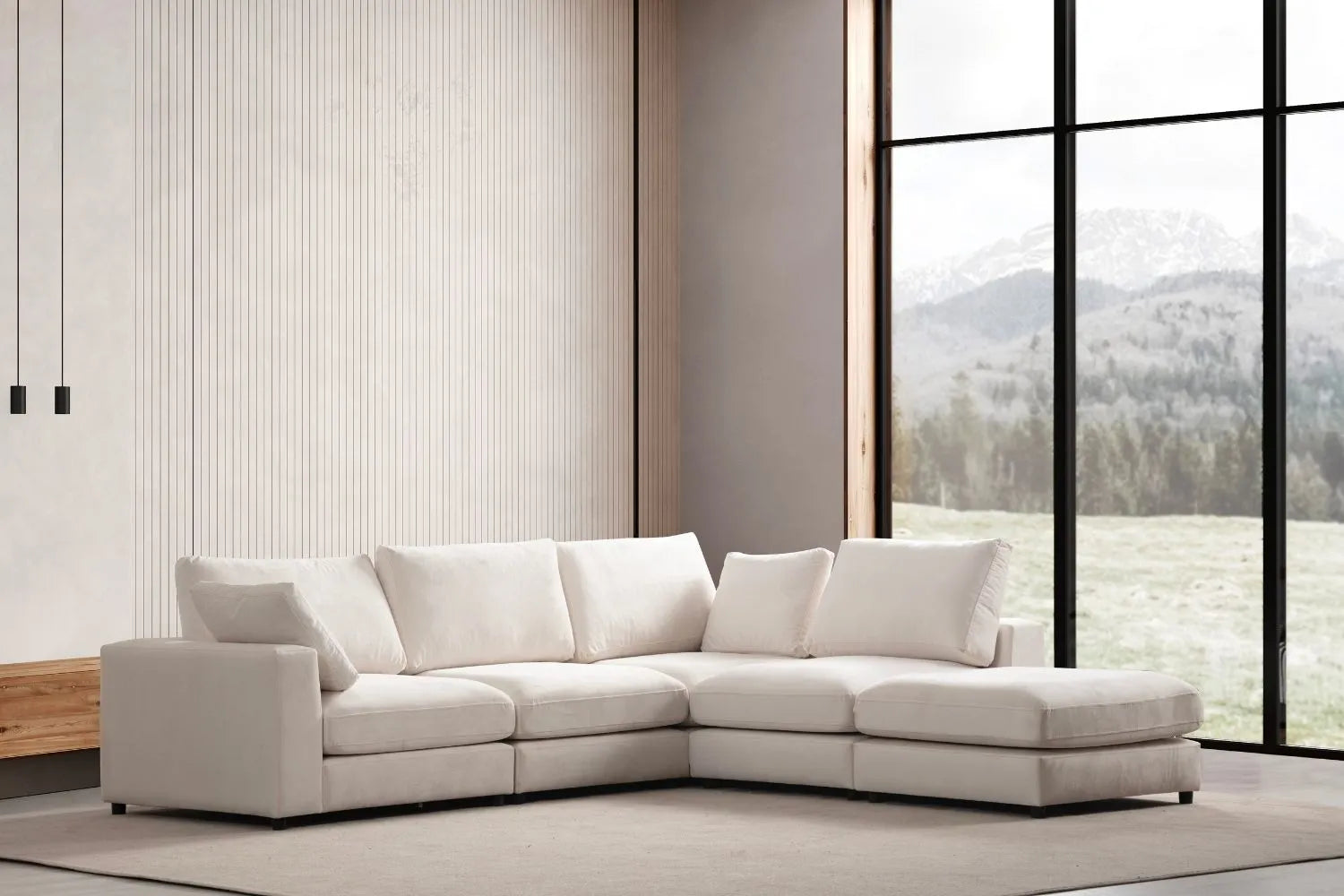 Canapé Julia modulable en velours blanc cassé avec 4 places et un pouf dans un salon minimaliste avec vue panoramique sur la nature.