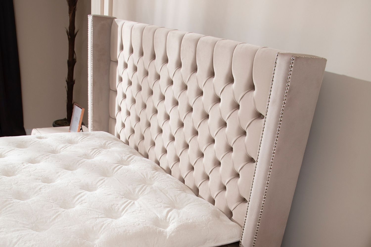 Zoom sur la tête de lit du lit coffre CLOUTE en velours beige, mettant en valeur les détails cloutés et la texture douce.