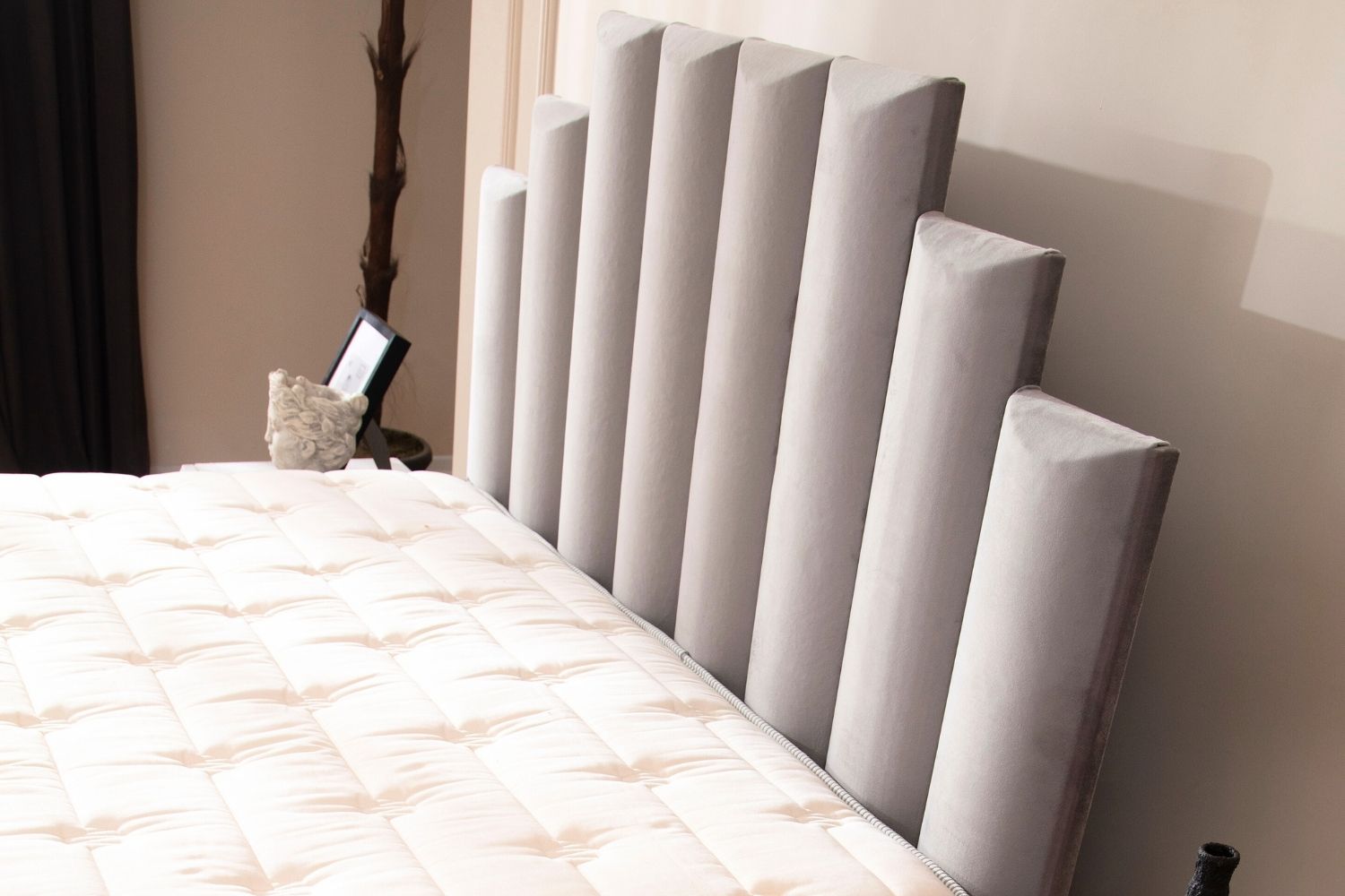 Zoom sur la tête de lit du lit coffre NATURA en velours gris, mettant en avant la texture luxueuse du velours et les détails du design.