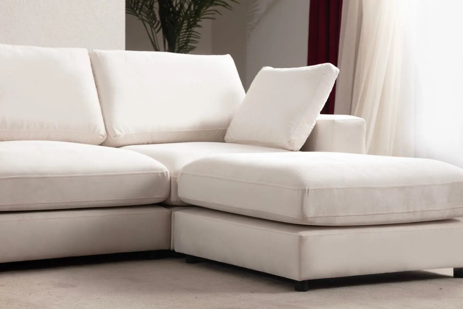 Gros plan sur les coussins et le pouf du canapé JULIA modulable en velours blanc cassé, mettant en avant les détails du tissu et du design.